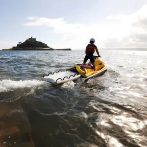 RNLI lifeguard on a rescue watercraft (RWC) with St Michaels Mount near Penzance in the background