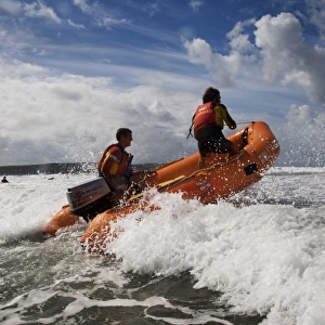 Two RNLI lifeguards in the surf at Woolacombe beach, Devon on an arancia inshore rescue boat