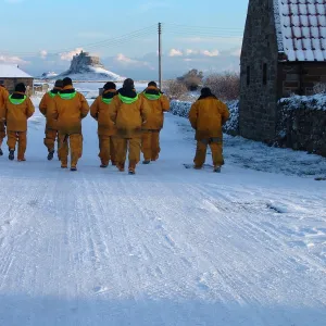 Seahouses crewmembers walk back to their lifeboat in the snow