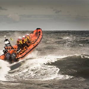 Sheringham Atlantic 85 inshore lifeboat The oddfellows B-818. Lifeboat is heading away from the camera over a breaking wave, bow high out of the water and four crew on board