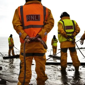 Shore helpers moving wooden rollers with ropes at Exmouth