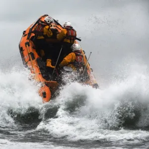 St Agnes D-class inshore lifeboat Blue Peter IV D-641 heading through a breaing wave. Crew members Gavin Purcell, Gavin forehead and Richard Llewellyn on board