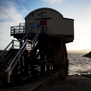 St Davids lifeboat station. Shot from behind the station looking out to sea, sun setting behind rocks in the distance
