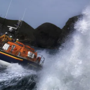 St Davids Tyne class lifeboat Garside 47-026 in rough seas. Three crew can be seen at the upper steering position. Lifeboat is breaking through a large wave and lots of white water