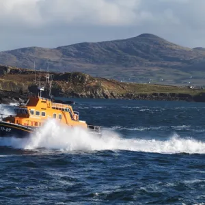 Valentia severn class lifeboat John and Margaret Doig 17-07. Lifeboat is moving from right to left in choppy seas, lots of white spray and waves breaking against cliffs in the background