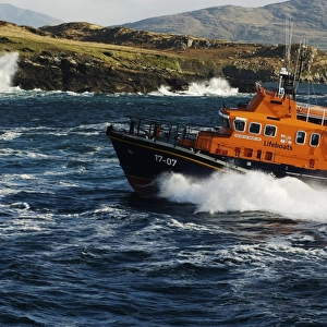 Valentia severn class lifeboat John and Margaret Doig 17-07. Lifeboat is moving from right to left in choppy seas, lots of white spray and waves breaking against rocks in the background