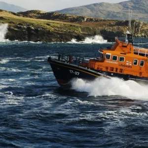 Valentia severn class lifeboat John and Margaret Doig 17-07. Lifeboat is moving from right to left in choppy seas, lots of white spray and waves breaking against rocks in the background