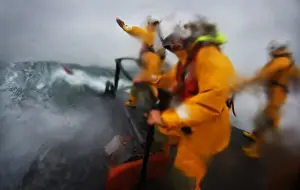 Crew on board relief Tamar class lifeboat Victor Freeman 16-13 wearing new lifejackets. Three crew on the bow of the lifeboat undertaking a search exercise