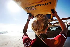 Female lifeguard lifting rescue boards down from a patrol vehicle