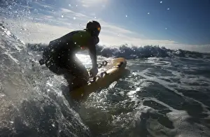 Female lifeguard paddling out through surf on a rescue board at Constantine Bay, Cornwall