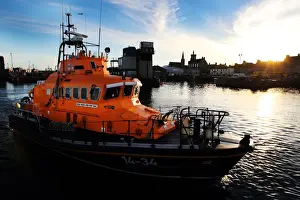 Fraserburgh Trent class lifeboat Willie and Mary Gall 14-34 in the harbour, sun low behind buildings in the background