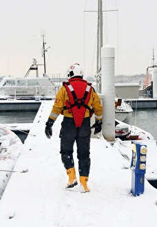 Lifeboat crew member walking along a snow covered pontoon at the Lifeboat College, Poole Lifeboat crew member walking along a snow covered pontoon at the Lifeboat College, Poole