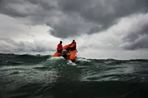 Two lifeguards on an arancia inshore rescue boat at Watergate Bay, Cornwall, headingaway from the camera