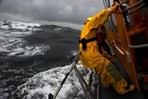 Lizard Tyne class lifeboat David Robinson 47-030 in rough weather. Crew members can be seen holding onto the side of the lifeboat as she lists over to the port side