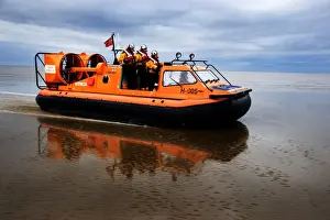 New Brighton hovercraft Hurley Spirit H-005 during a training exercise on mudflats. Four crew in view, hovercraft moving from left to right