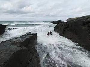 Reconstruction of the rescue of a fisherman by two RNLI lifeguards Chris Boundy and John Dugard at Trebarwith Strand, Cornwall. Picture shows the two lifeguards struggling through surf in the area called the Washing Machine, fisherman on rocks
