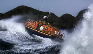 St Davids Tyne class lifeboat Garside 47-026 in rough seas. Three crew can be seen at the upper steering position. Lifeboat is breaking through a large wave and lots of white water