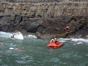 <b class=qtipBold><figcaption>Swanage D-class lifeboat</figcaption></b><br>Yacht stricken against cliffs. RNLI crew member on cliffs with rescued casualty. Swanage D-class lifeboat with two crew and one other rescued casualty in boat facing towards the left of the camera.<br><em>© RNLI 2008 - All Rights Reserved</em> Swanage D-class lifeboat